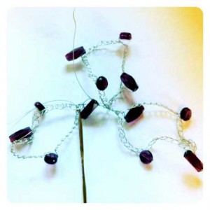 Crocheting with wire and purple beads to make a bracelet